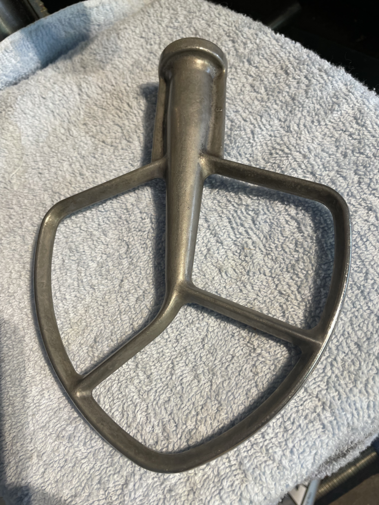 A flat KitchenAid K5 series beater, uncoated, after dishwashing.